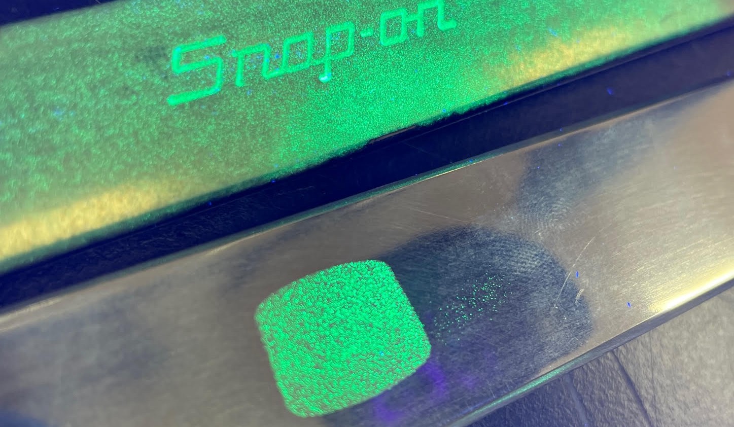 Snap-on tool surface with fluorescent Glow Powder under UV light